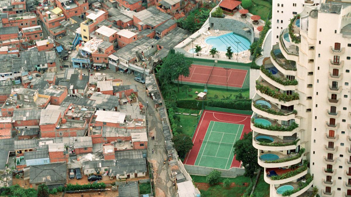 ariel photograph of high rise with pools next to shanty town