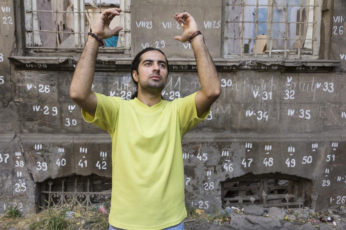 man in yellow t-shirt in front of building