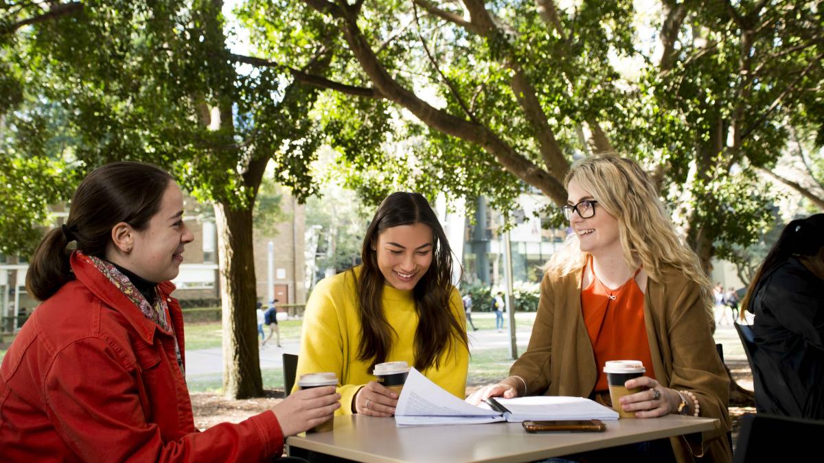photo of three women sitting at a table outside
