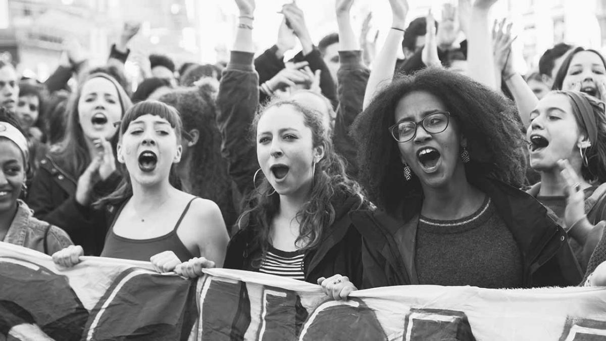 Young women protesting, holding a banner.