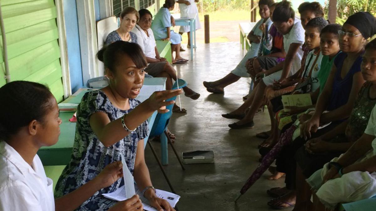 phot of health worker explaining to a group of women outdoors