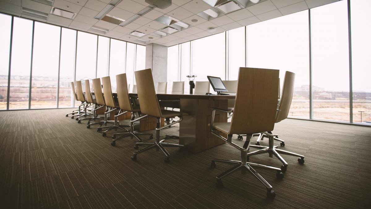 photo of a corprate board room with chairs around a long desk and large windows