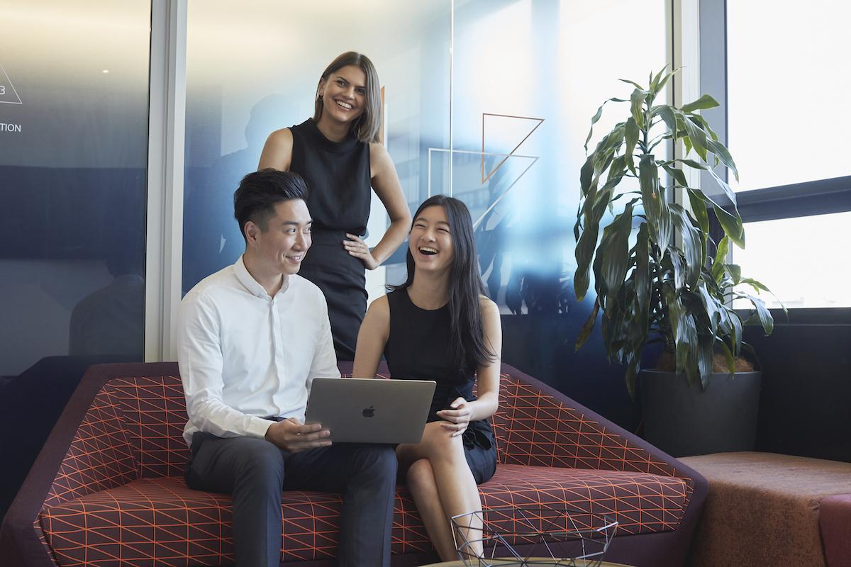 group of young people with a laptop sitting on a sofa
