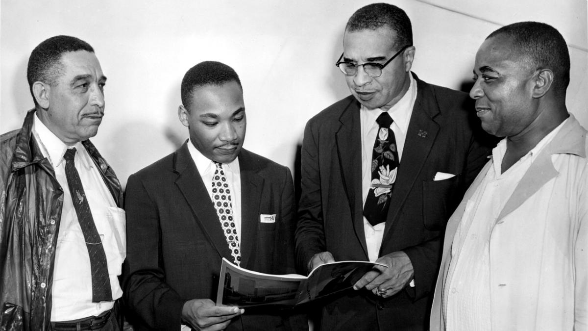 A group of four men, including Marting Luther King and Walter L Perry, congregating. 